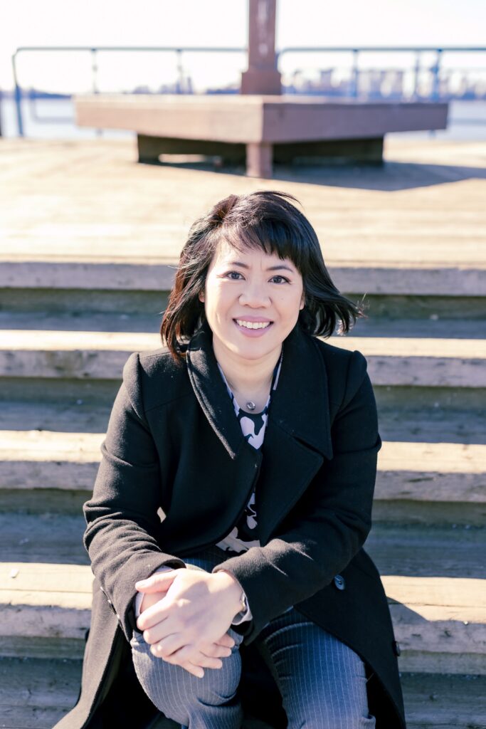 Michelle Chow in a black jacket sitting on steps