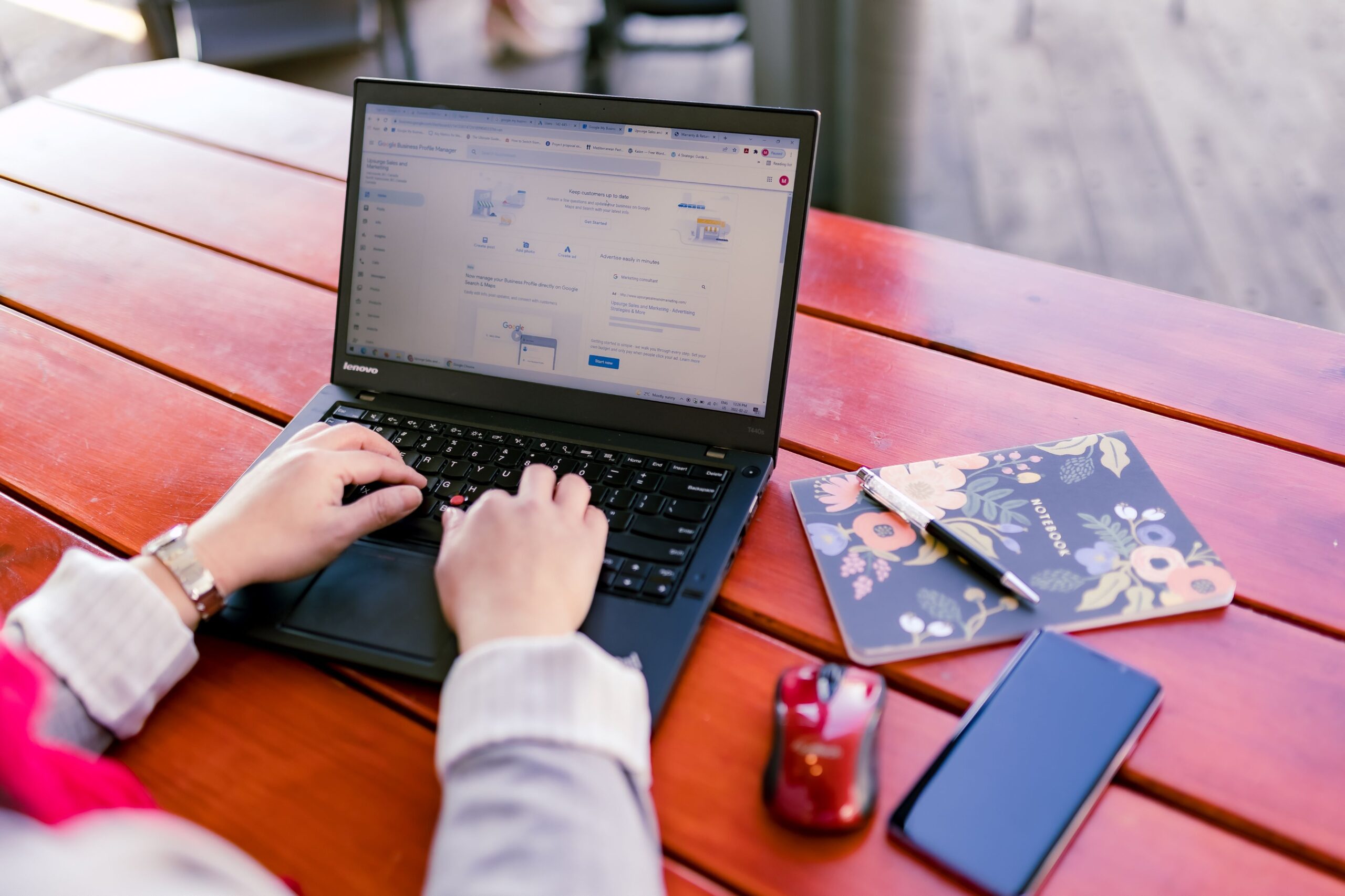 Michelle Chow working on a laptop with a mouse, cell phone, and notebook
