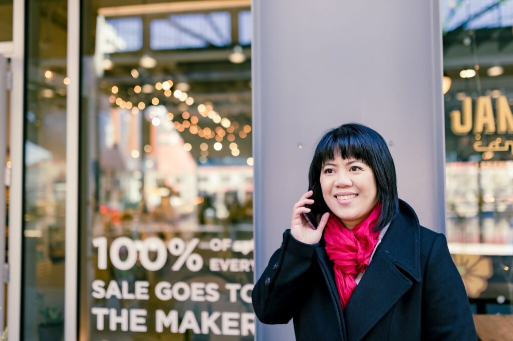 Michelle Chow of Upsurge Sales and Marketing on the phone and standing outside a store